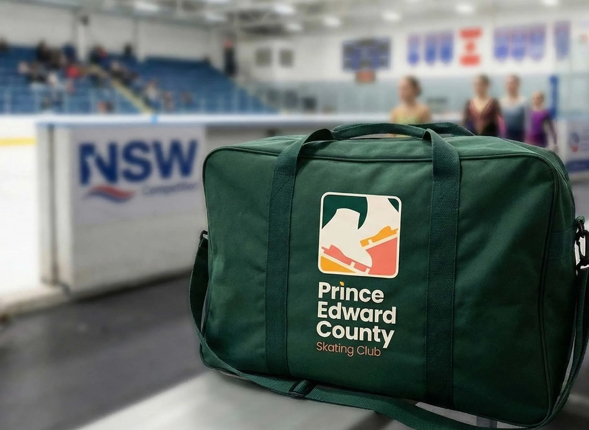 Branded forest green equipment bag with the skating club logo at the rink